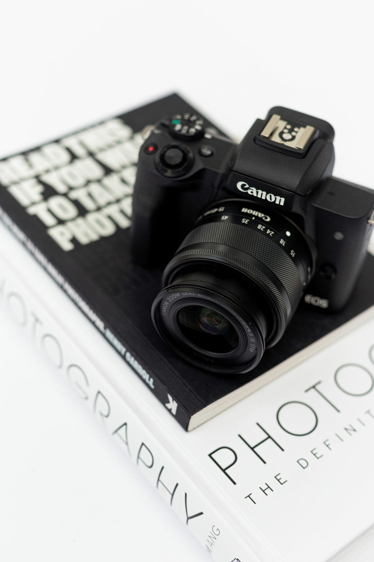 Black and white shot of a Canon camera placed on a stack of art-style books.